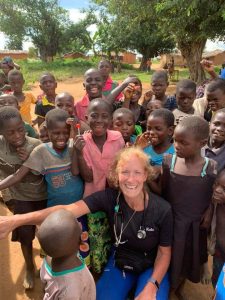 Dr. Kolo smiles at the camera, surrounded by smiling children.