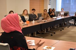 Alaa speaks to a group of peers around a conference table.
